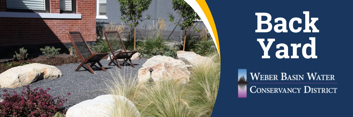 Back Yard. Two chairs on a gravel patio among boulders and ornamental grasses. Weber Basin Water Conservancy District